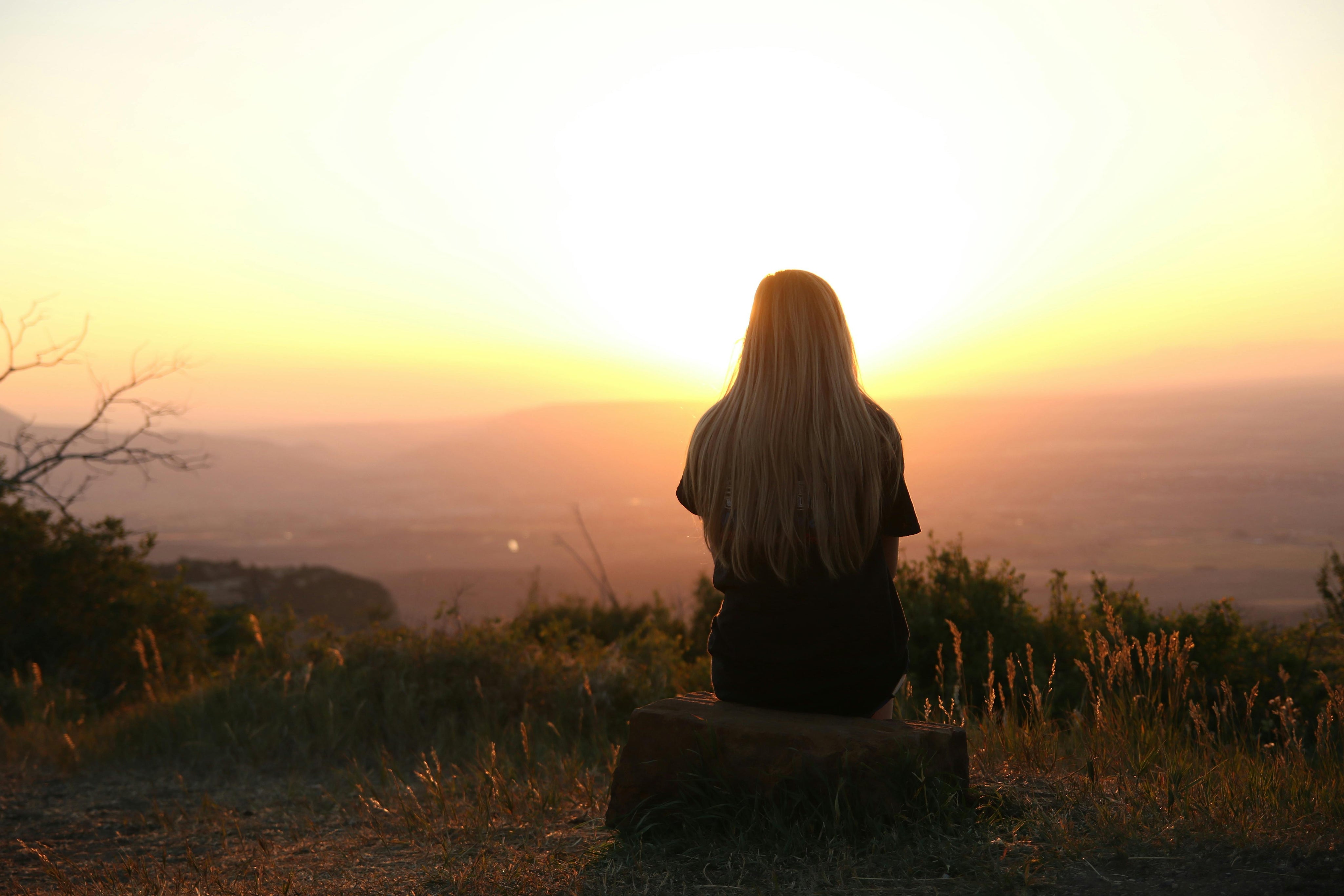 Une femme regarde le coucher de soleil dans la montagne