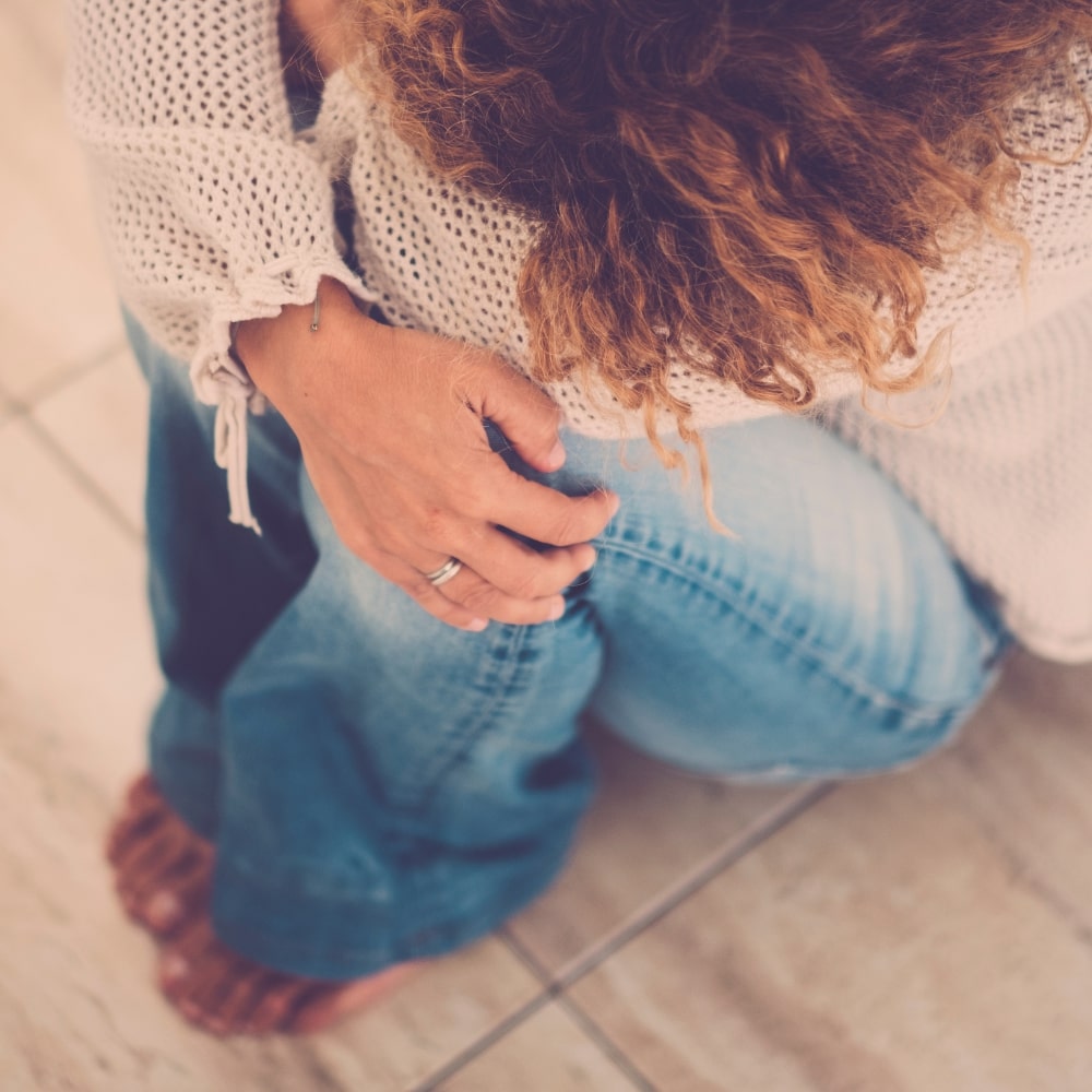 Une femme ménopausée est assise, recroquevillée