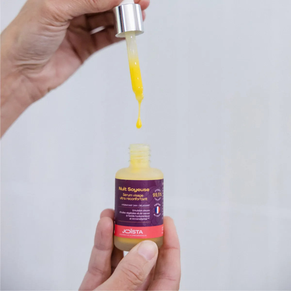 Une femme prend une goutte du serum hydratant nuit soyeuse de Joïsta